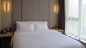 A hotel room with a large bed, two bedside tables, a nightstand, and a window with curtains. - Lavande Hotel Shanghai Zhangjiang Guanglan Road Me (Shanghai)