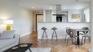 Uma sala de estar moderna com sofá, mesa de centro e área de jantar com cadeiras e mesa.