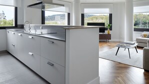 Uma cozinha moderna com uma ilha grande, eletrodomésticos embutidos e amplas janelas com vista para a cidade.