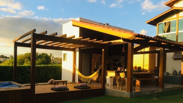 A covered outdoor patio with a hammock, seating, and a pool area. - Cozy Wooden House (Formiga)