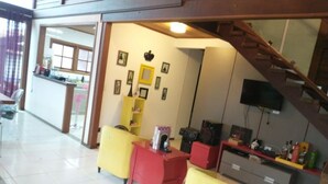A hotel lobby with yellow and red seating, a staircase, and a TV mounted on the wall. - Cozy Wooden House (Formiga)