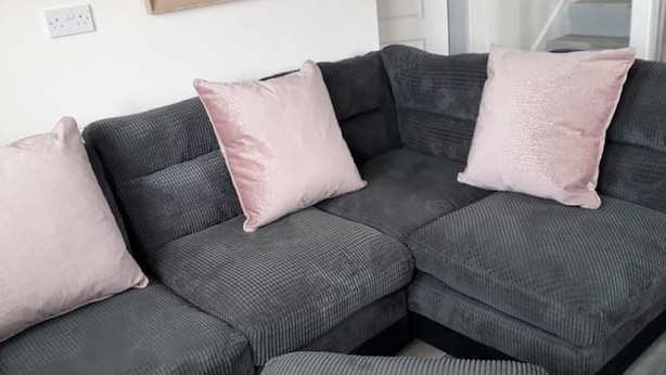 A grey sectional sofa with two pink cushions and a matching ottoman. - Stunning Tory Island Apartment (Tory Island)