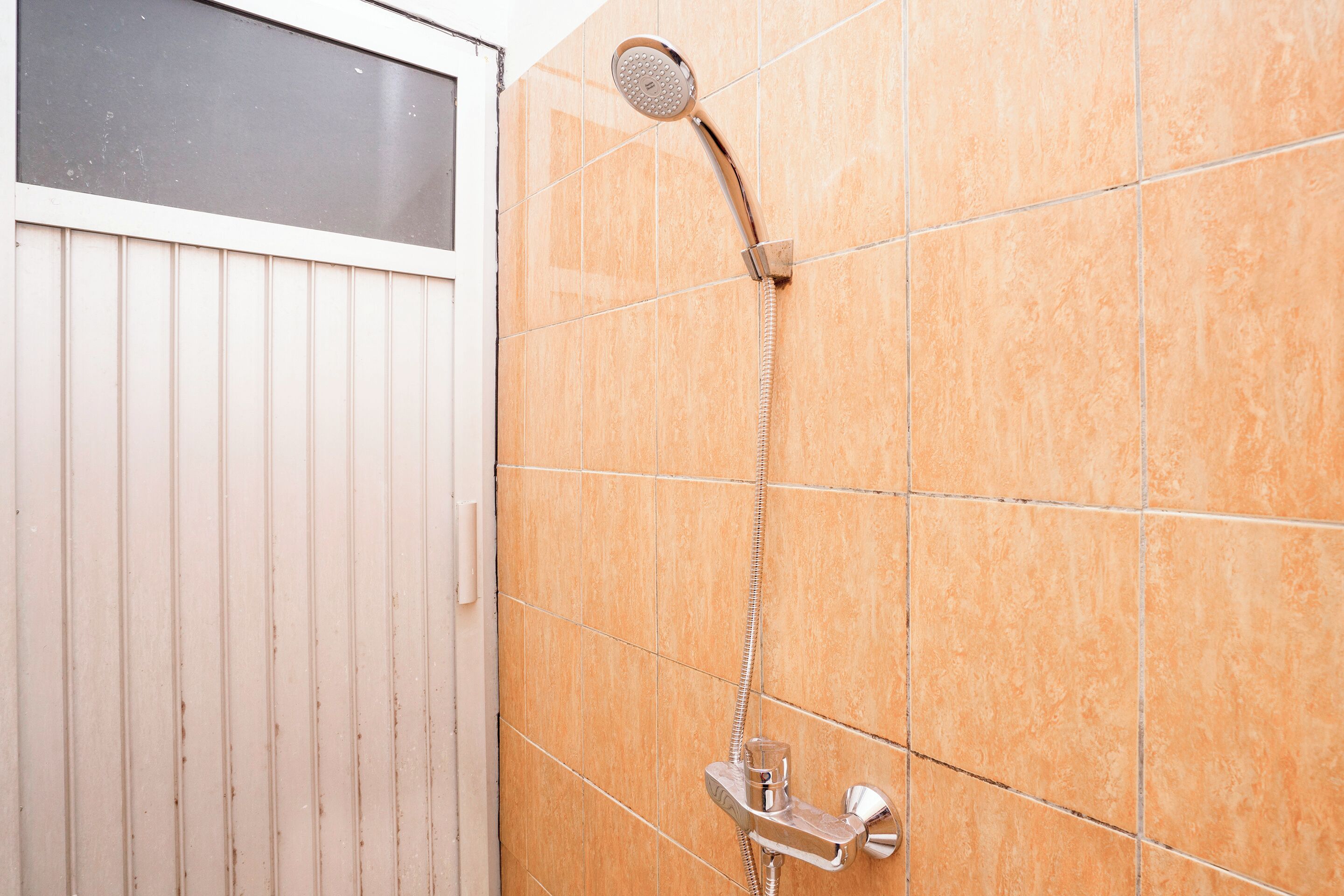 A bathroom with a shower, tiled walls, and a wooden door.