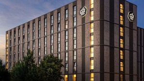 A modern hotel building with a brick facade, multiple windows, and illuminated signage. - Arthotel ANA Amber (Rostock)