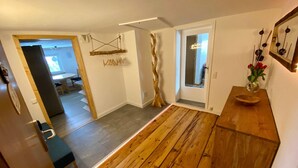 Un interior moderno con suelo de madera, un banco de madera, una escultura de árbol decorativa y un jarrón con flores sobre una mesa de madera.