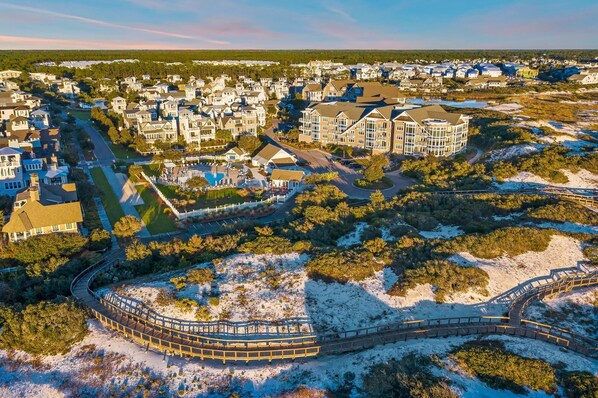 A coastal residential area with a large house featuring a swimming pool and a wooden boardwalk.