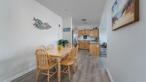 Un comedor con una mesa y sillas de madera, una cocina con armarios de madera y un cuadro en la pared.