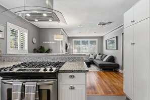 A modern kitchen with a gas stove, white cabinets, and a granite countertop. - Littleton Cottage🏡2 blocks to Main🛍️Pets🐶Fenced Yard♨️Firepit🤑0 Cleaning & Pet Fee (Littleton)