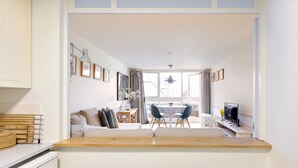 A modern living room with a sofa, a dining table with chairs, a TV, and a kitchen area with a counter and a sink. - St Katharine Dock | By Tower Bridge | Dock View (London)