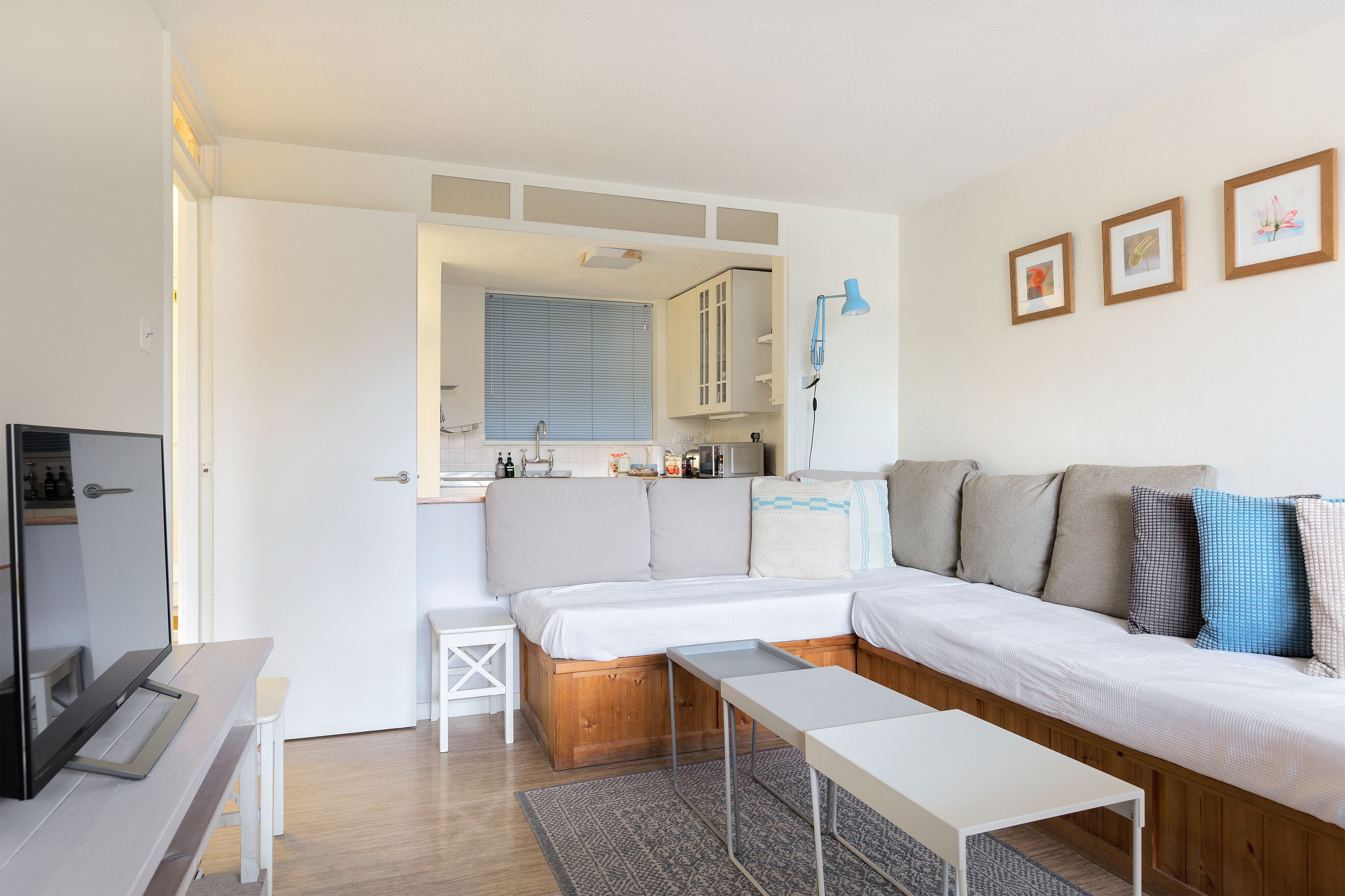 Une pièce moderne et bien éclairée, comprenant un canapé, une petite table et un coin cuisine.