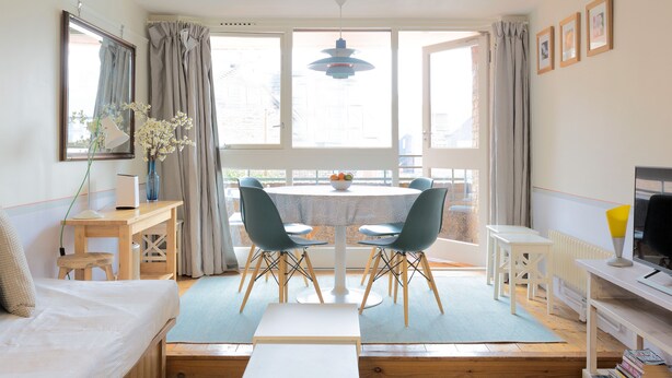 A bright, open-plan living space with a dining area, a sofa, a TV, and a window with curtains. - St Katharine Dock | By Tower Bridge | Dock View (London)