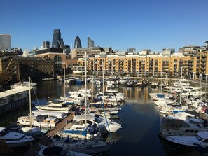 A marina with multiple boats docked, surrounded by urban buildings and a clear sky. - St Katharine Docks | By Tower Bridge | Studio Flat (London)