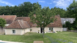 A residential property with a swimming pool, a small garden, and a brick house with a tiled roof.