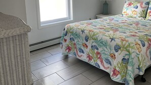 A bedroom with a bed, a window, a ceiling fan, and a wall-mounted lamp. - Seashell Cottages/JK Rentals -  The Daniel Unit (Old Orchard Beach)