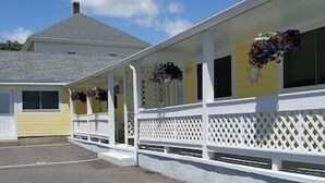 A motel with a covered parking area and a building with a white picket fence. - Seashell Cottages/JK Rentals -  The Daniel Unit (Old Orchard Beach)