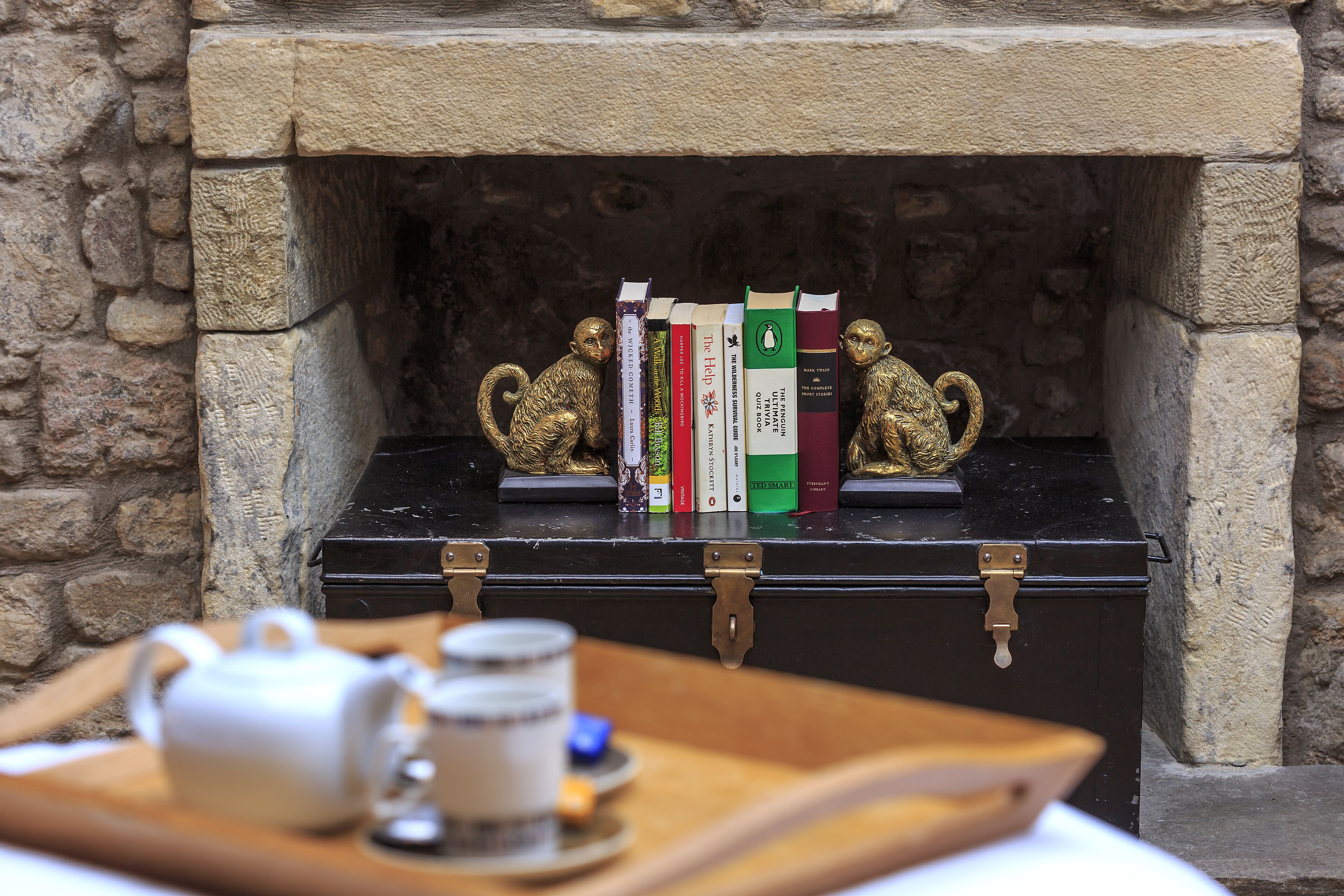 A fireplace with a bookcase and two monkey figurines.