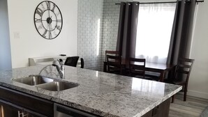 Una cocina moderna con encimera de granito, pileta de acero inoxidable y lavavajillas.