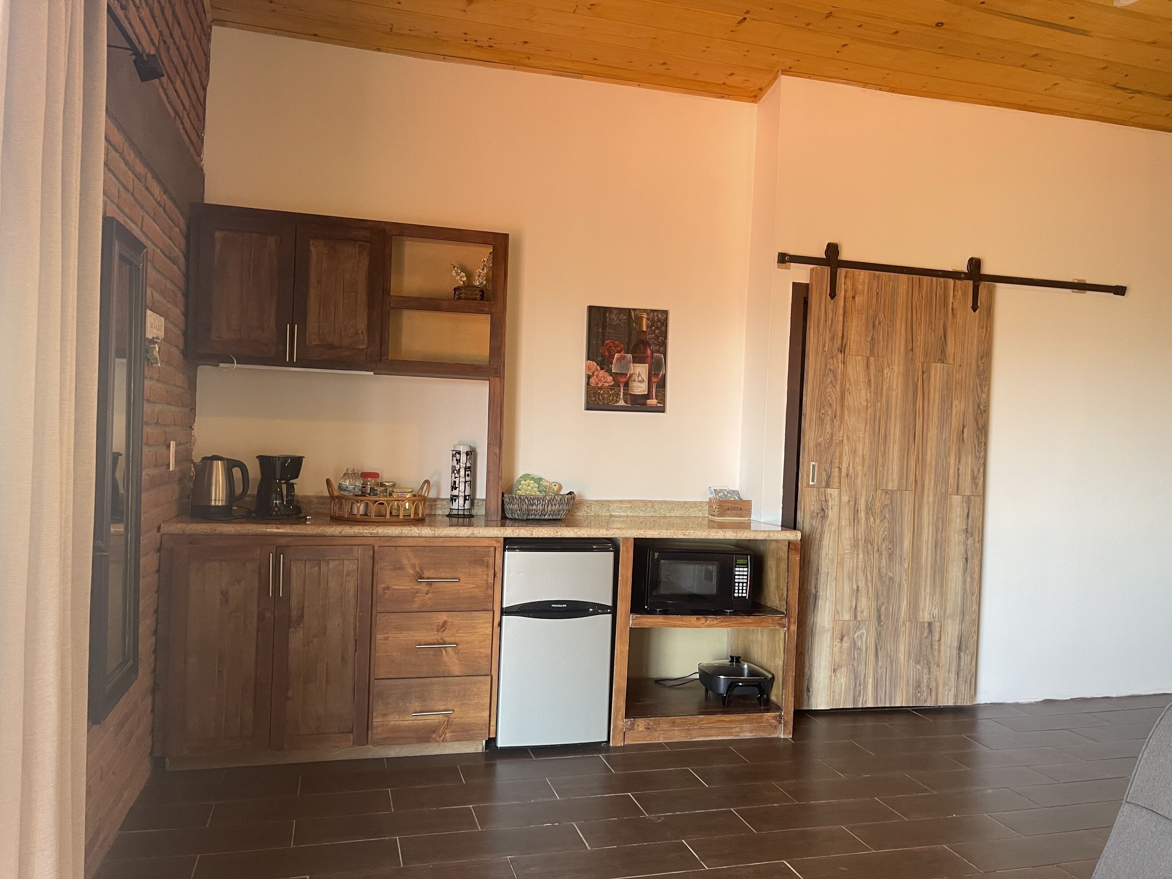 A kitchen with wooden cabinets, a refrigerator, a microwave, and a sliding door.