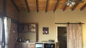 A kitchen with wooden cabinets, a refrigerator, a microwave, and a ceiling fan.