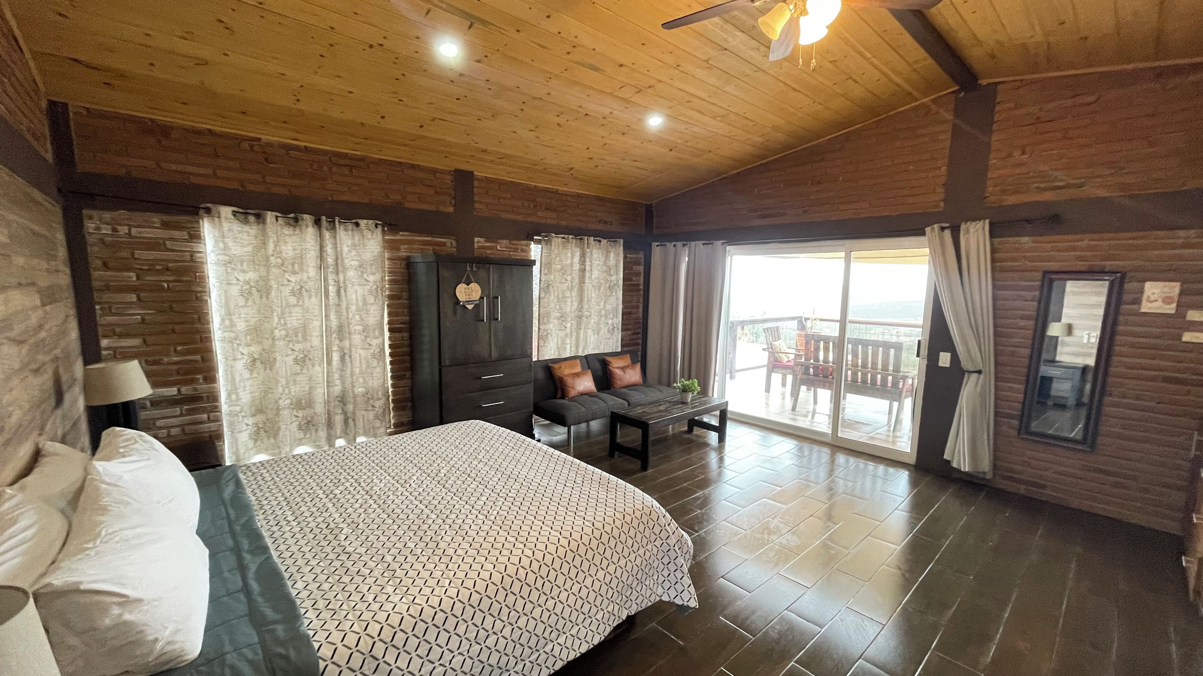 Une chambre à coucher comprenant un lit, un canapé, un bureau et un balcon aménagé avec du mobilier d’extérieur.
