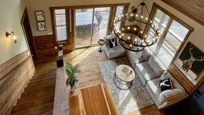 Ein geräumiger Lofts mit hohen Decken, großen Fenstern, einer Holztreppe und einer gemütlichen Sitzecke mit einer Chandelüster.