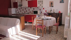 Una cocina compacta con gabinetes rojo y blanco, un microondas y un comedor con mesa dispuesta para cuatro.