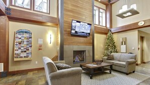 Eine großzügige Lobby mit Kamin, bequemen Sitzgelegenheiten, einem Weihnachtsbaum und einem großen Bildschirm.