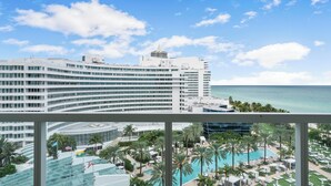 Un hotel con area piscina, palme e vista sull'oceano.