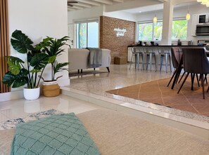 A modern living area with a kitchen, bar stools, and a large potted plant. - Bright & Spacious 4 mi to BEACH +Big Backyard (Miami)