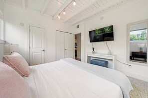 Une chambre à coucher avec un lit, un téléviseur fixé au mur et une fenêtre donnant sur un beau paysage.