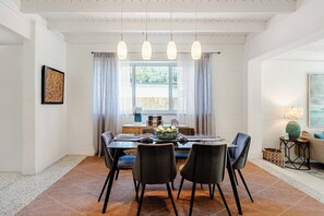 A dining area with a table, chairs, pendant lights, and a window with curtains. - Bright & Spacious 4 mi to BEACH +Big Backyard (Miami)