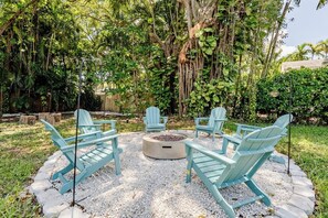 A circular seating area with Adirondack chairs around a central fire pit, surrounded by a gravel border and lush greenery. - Bright & Spacious 4 mi to BEACH +Big Backyard (Miami)