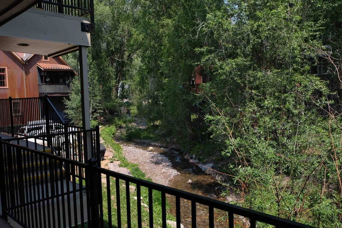 A balcony with a view of a river and dense greenery.