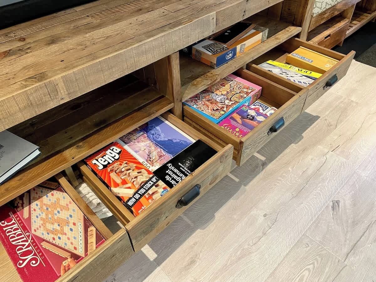 Een houten kast met meerdere lades vol met verschillende bordspellen.