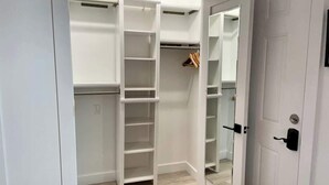 Un dressing accessible sans porte, doté d’étagères ouvertes et d’une porte de placard miroir.