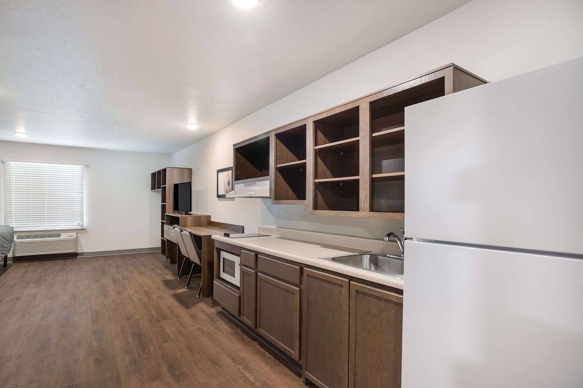 A modern kitchen with wooden cabinets, a built-in oven, and a stainless steel sink.