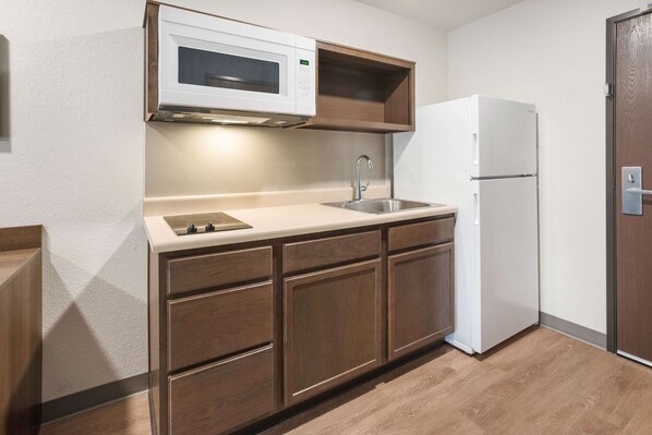 A compact kitchen with a microwave, sink, and refrigerator.