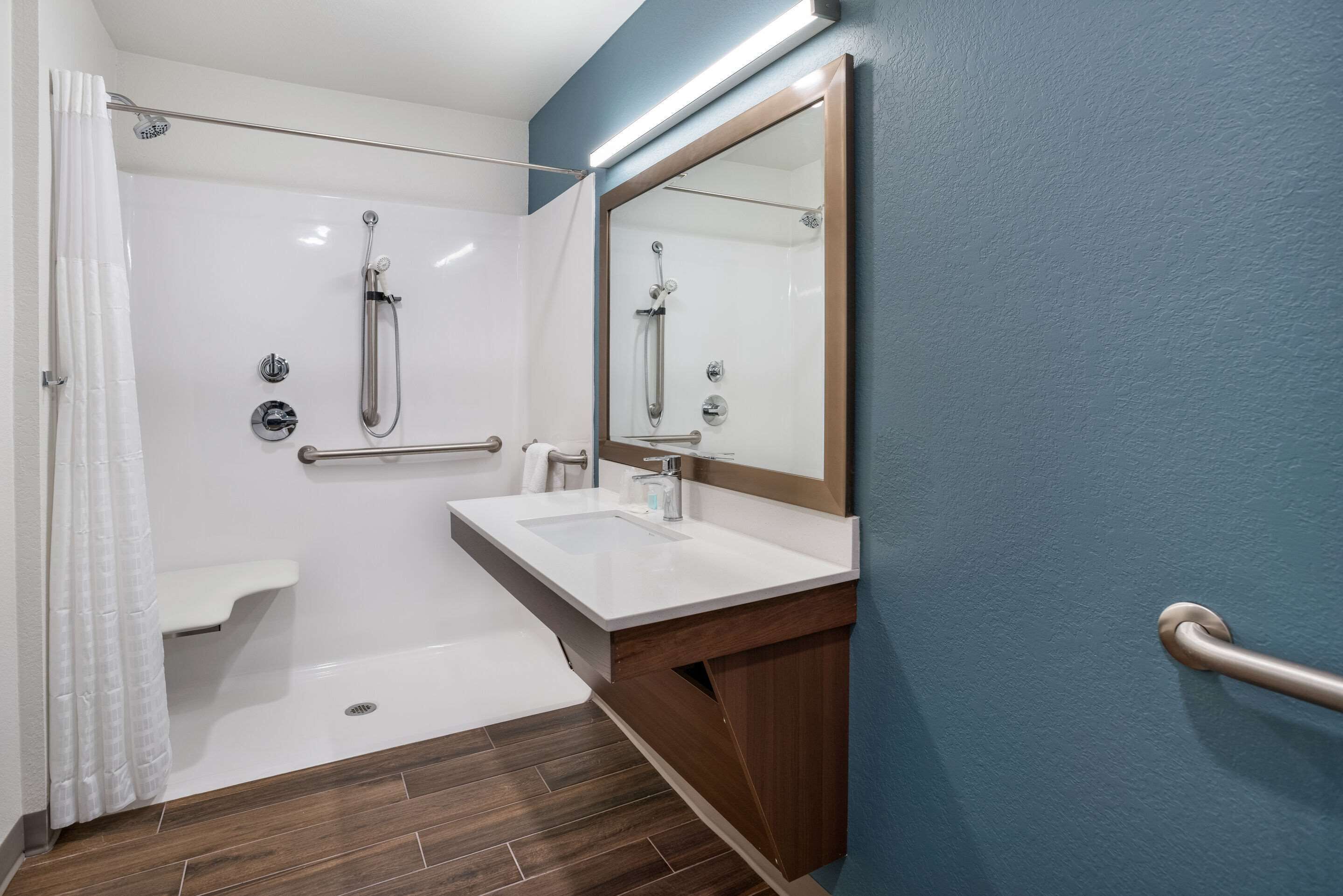 A modern bathroom with a shower, a sink, and a mirror.