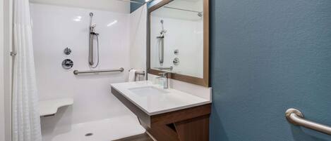 A modern bathroom with a shower, a sink, and a mirror.