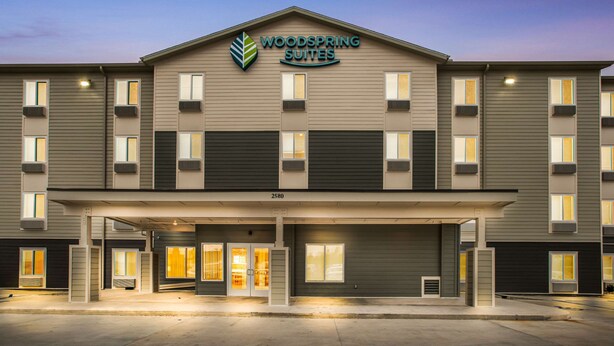A multi-story hotel with a flat roof, large windows, and a prominent signage for "Woodspring Suites." - WoodSpring Suites Sulphur - Lake Charles (Sulphur)