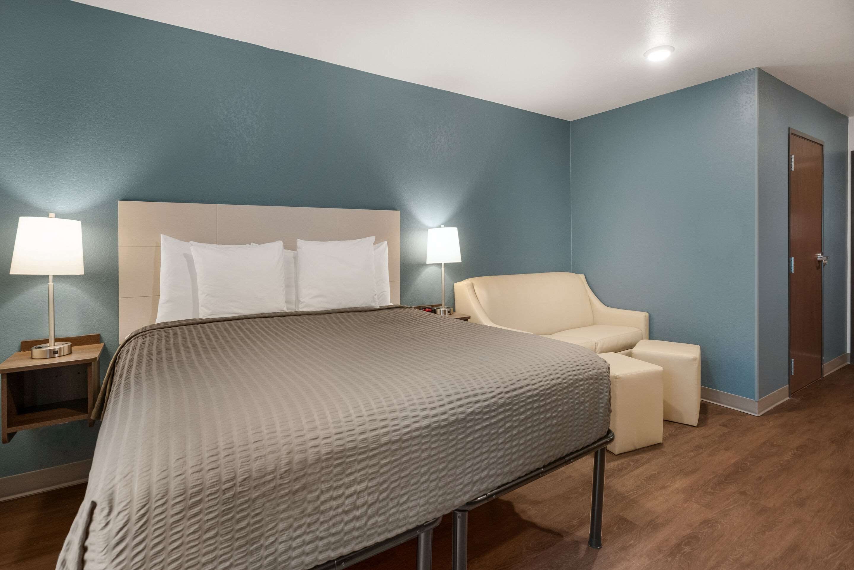 Een hotelkamer met een bed, twee bedlampen, een stoel en een nachtkastje.