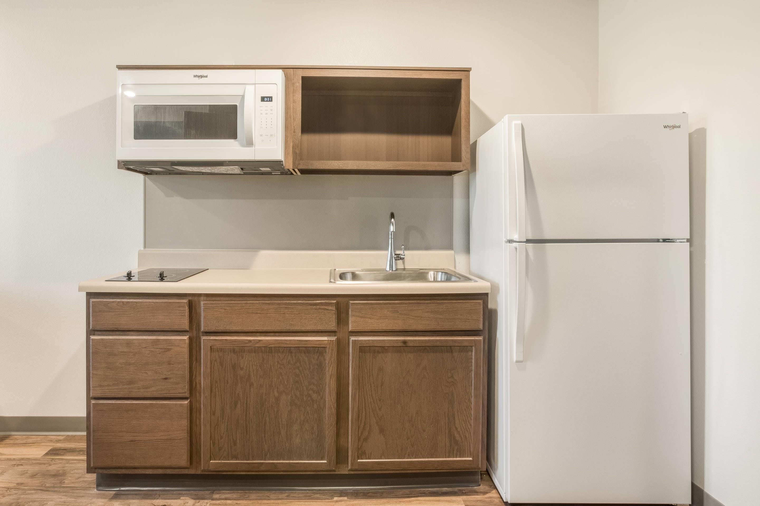 A compact kitchen with a built-in microwave, a sink, and a refrigerator.