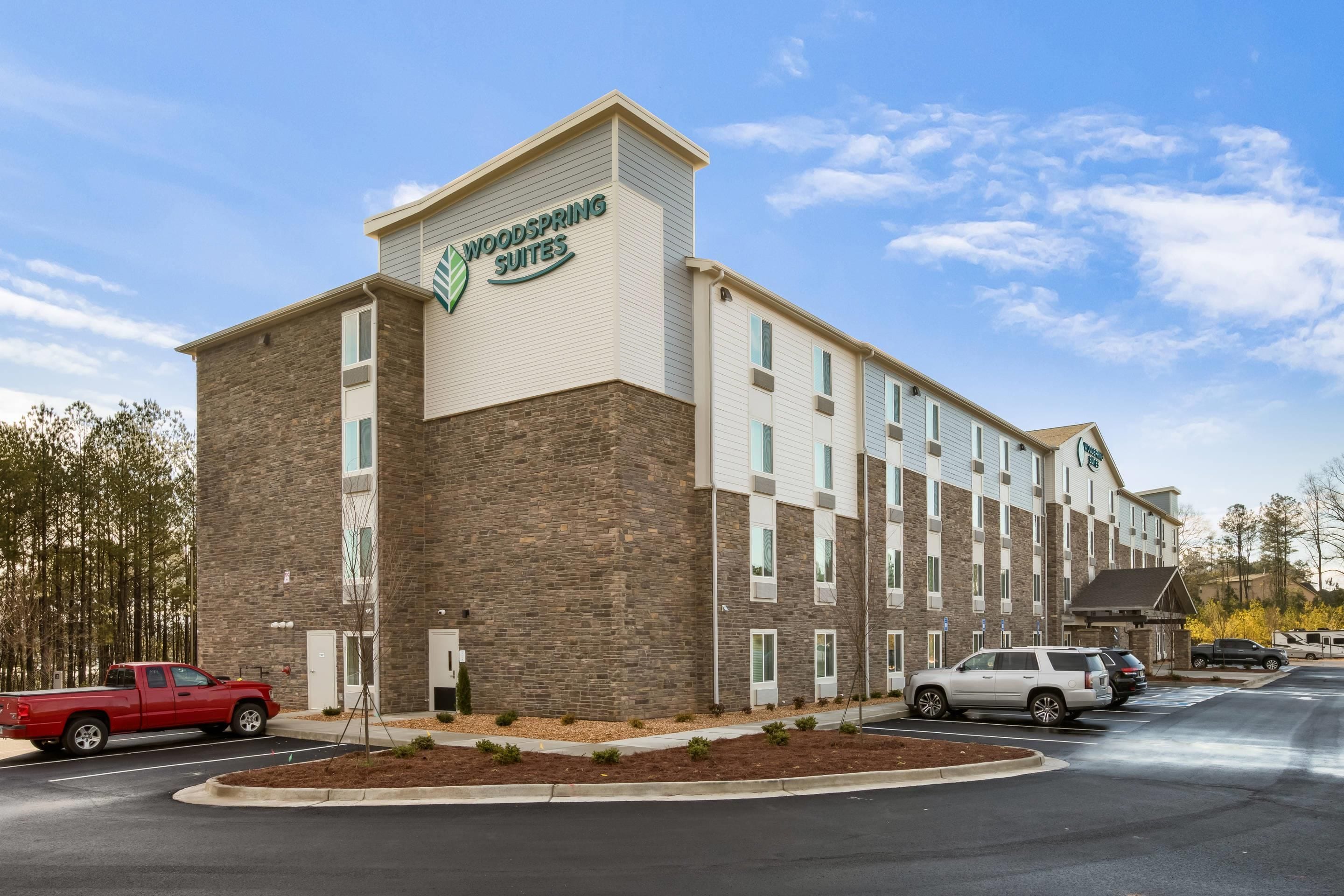 A multi-story hotel with a brick facade and a sign reading 'Woodspring Suites.'