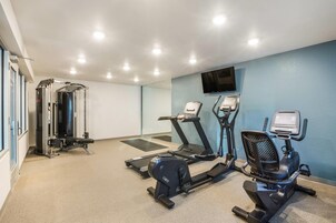Un gimnasio equipado con cinta de correr, elíptica y máquina de pesas.