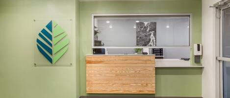 A reception area with a wooden counter, a framed abstract artwork, and a window with a waterfall view.