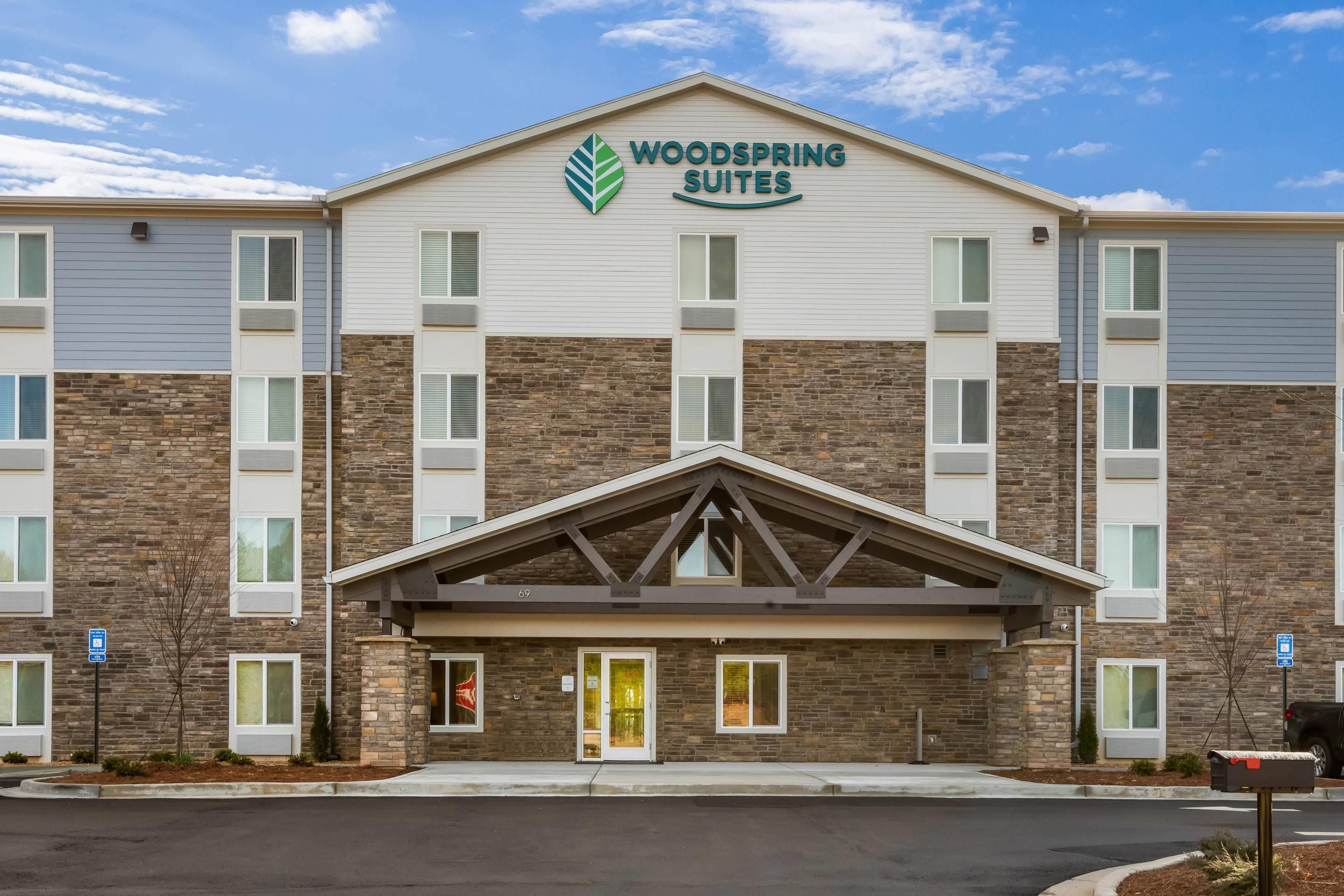 A multi-story hotel with a prominent 'Woodspring Suites' sign.