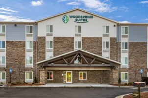 Un hotel de varios pisos con un llamativo letrero de 'Woodspring Suites'.