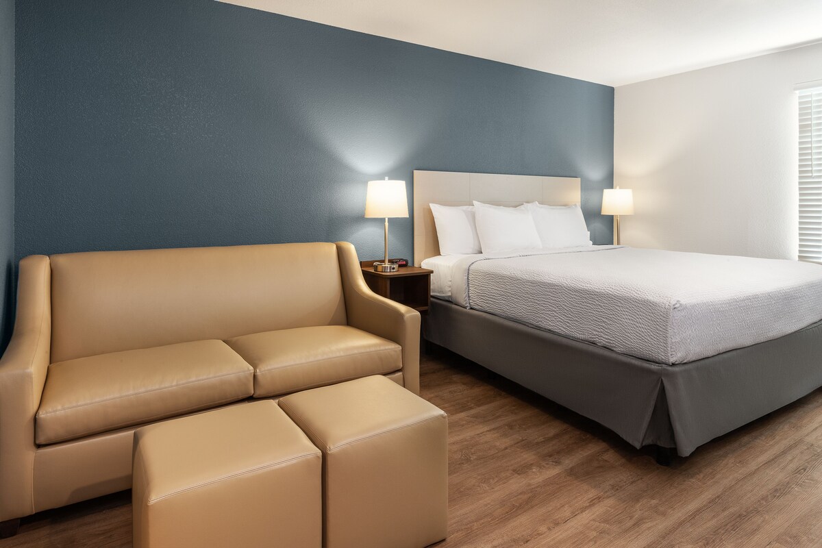 A hotel room with a bed, a sofa, and two nightstands with lamps.