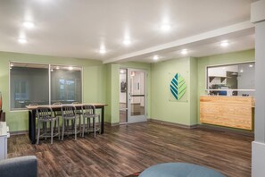 A conference room with a table and chairs, a reception desk, and a door leading to a hallway. - WoodSpring Suites Atlanta Newnan (Newnan)