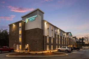 A hotel with a sign reading 'Woodspring Suites' and a parking lot with vehicles. - WoodSpring Suites Atlanta Newnan (Newnan)